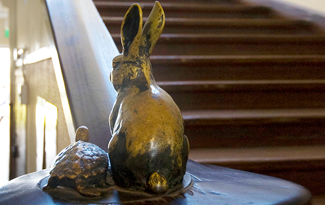 The banister rails are decorated with the brass figures of a rabbit and a turtle competing with each other.